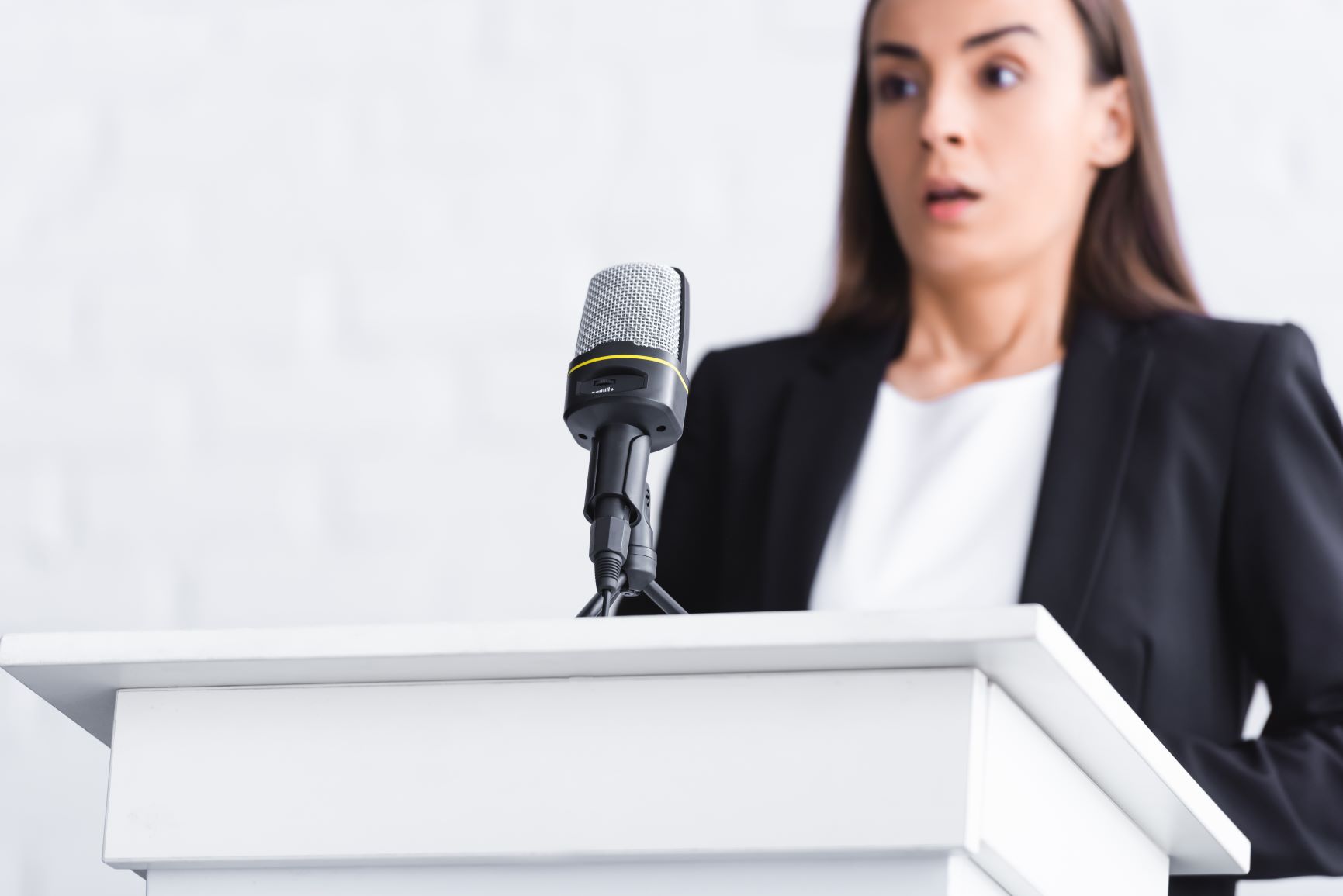 Overcome fear by facing fear. Woman afraid of public speaking looks panicked.