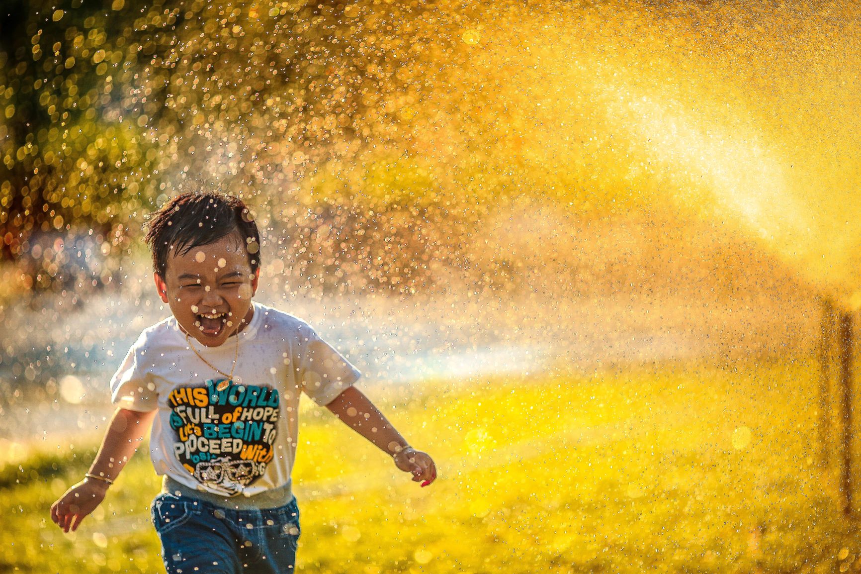 Overcome fear by stealing back happiness and abundance we are all born with. Happy boy running through sprinklers.