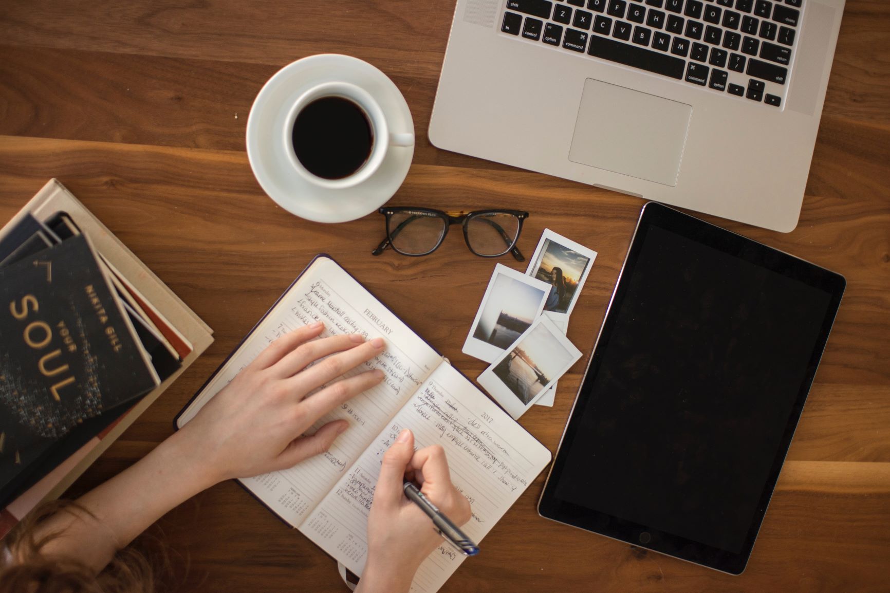 Woman sitting at desk, writing in notebook. Practice five minute rule and work five minutes when you don't feel like it